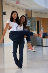 Female student carrying her friend at school and smiling